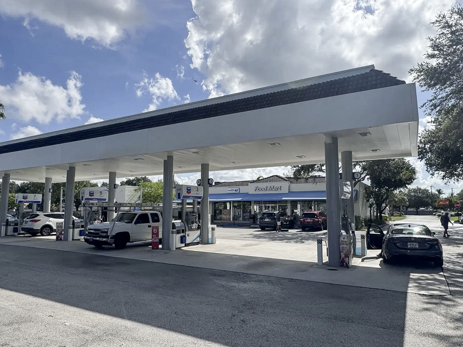 Chevron fuel forecourt with canopy, dispensers, and convenience store